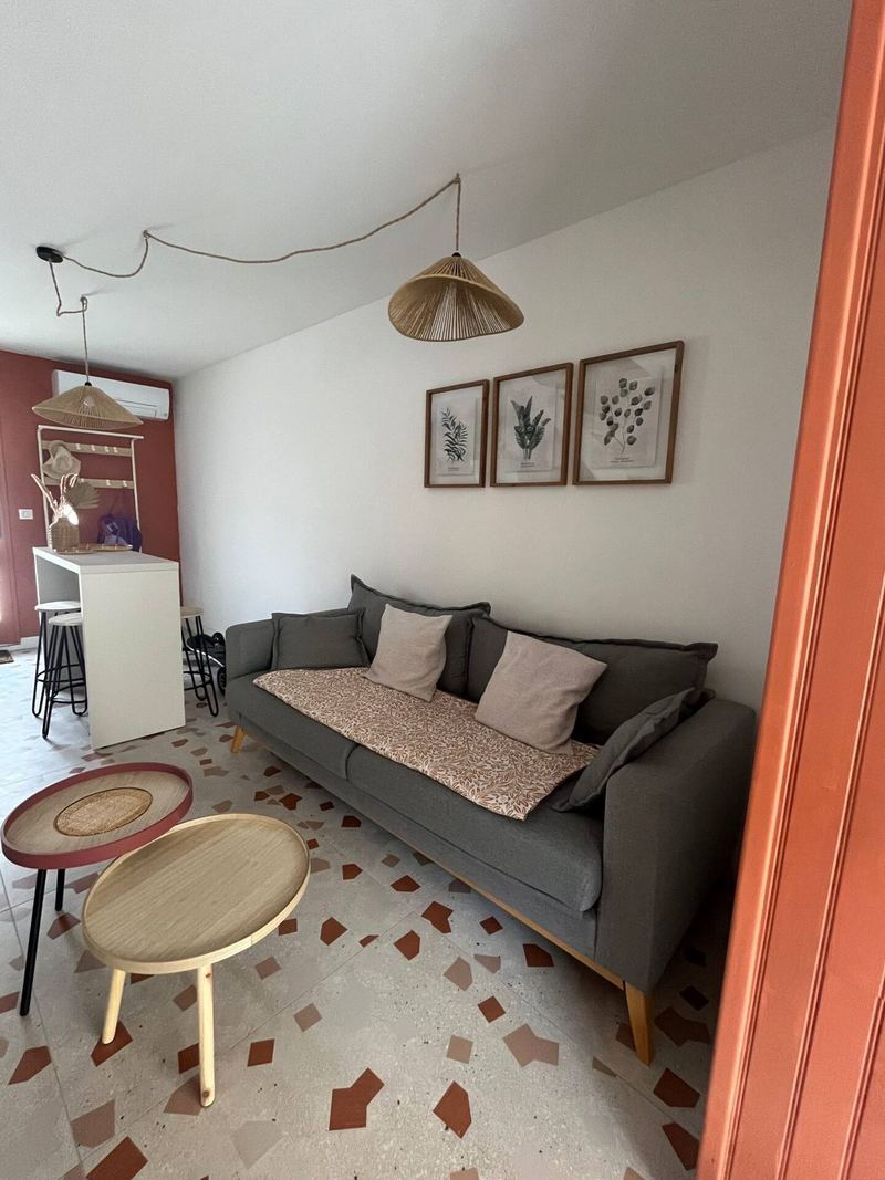 Salon avec canapé gris, cadres botaniques et tables basses en bois